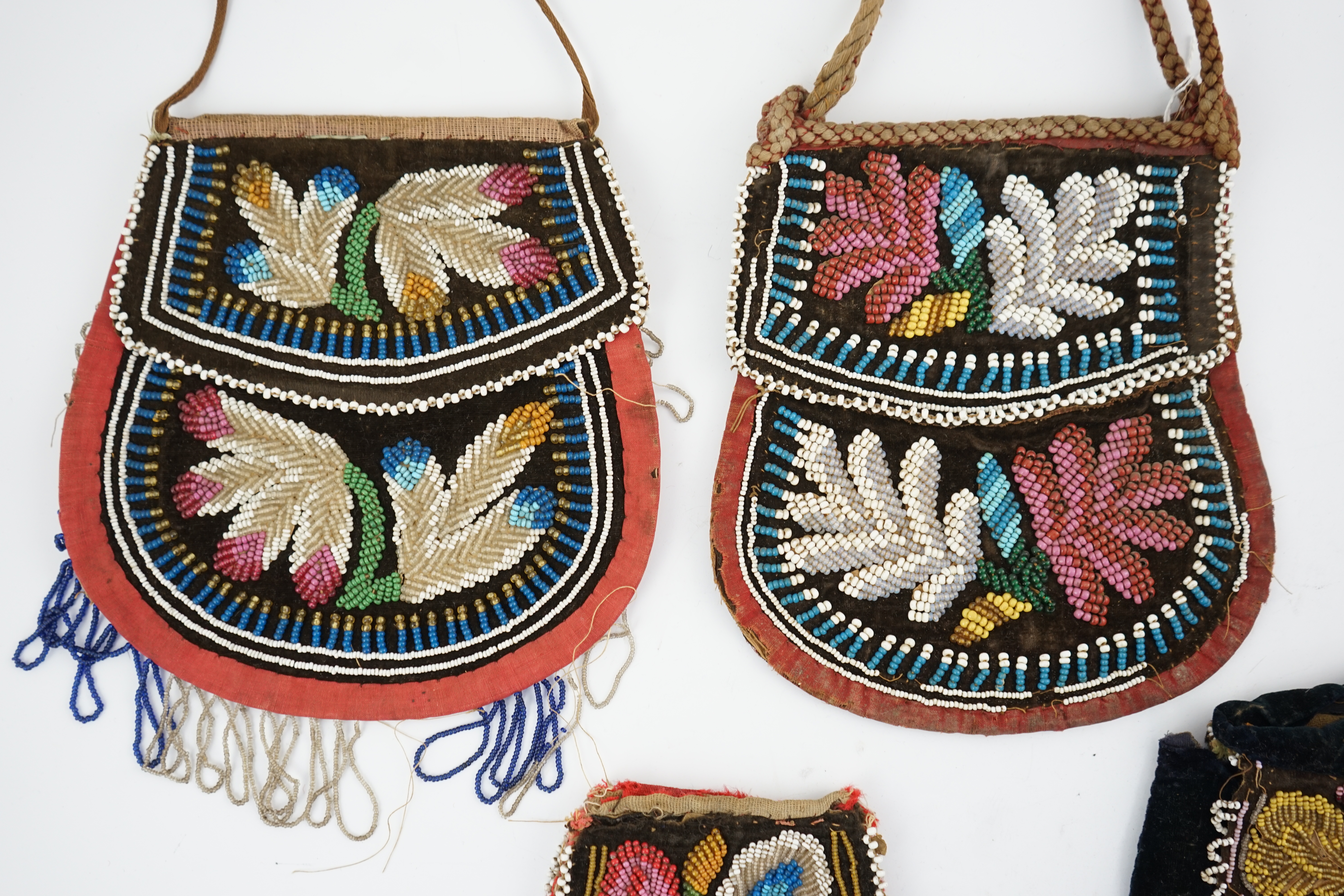 Four 19th century Iroquois Native American beaded bags, three large and one smaller, all bags worked in various colours and differing designs, all with flaps and same pattern both sides, largest 19cm high. Condition - al